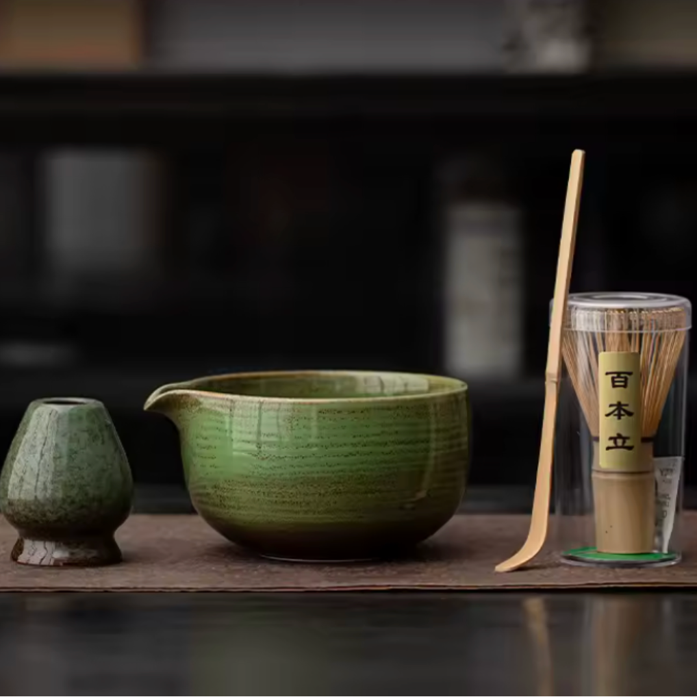 Green ceramic tea set with a wooden spoon and glass container on a dark surface.